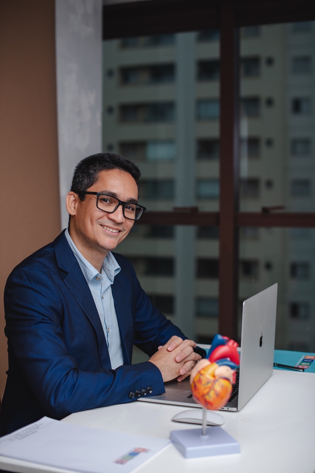 Dr. Alessandro à mesa com modelo anatômico do coração